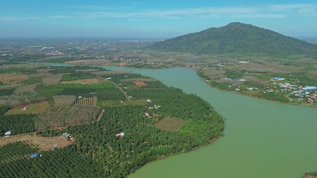 Drone aerial pan over patchwork farmland around Thac Mo Reservoir under bright sun in Southern Vietnam.