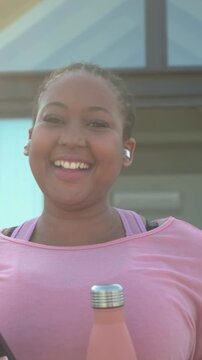 Vertical video: Reacting to text woman in pink top laughing checking phone at door holding bottle