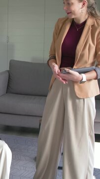 Vertical video: Responding to peer raising hand, woman in blazer gesturing with tablet at office