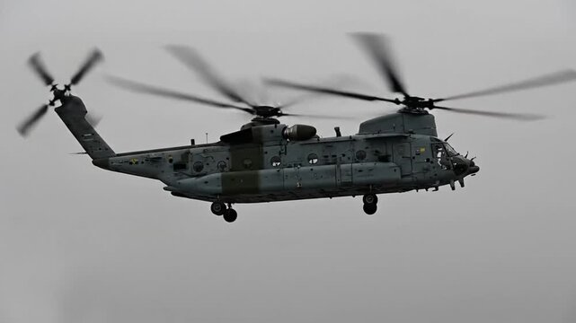 Military helicopter in flight against a cloudy gray sky displays impressive aerial prowess and operational capability