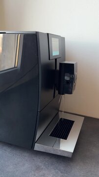 Automatic coffee machine rinse. Water leaking from the coffee machine. An expensive coffee machine with an automatic self-cleaning system. A black coffee machine in the interior.