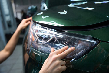 Professional auto detailer is applying protection film to automotive headlight © Viacheslav Yakobchuk