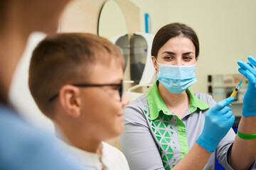 Healthcare professional administering injection to young boy indoors