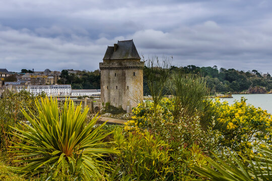 Tour Solidor &agrave; Saint-Malo sous un ciel mena&ccedil;ant avec au premier plan des arbustes fleuris.