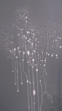 Glass cleaner spray on mirror and hand wiping surface with white paper napkin cleaning service concept, vertical video