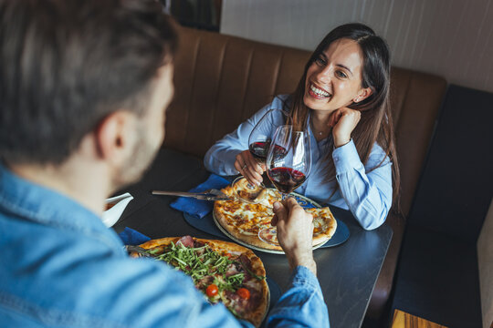 Happy Couple Sharing Pizza and Red Wine on a Romantic Date Night in a Cozy Restaurant