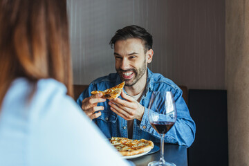 Smiling Man Enjoying Pizza and Red Wine on a Casual Restaurant Date With Partner