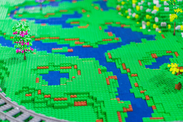 Fototapeta premium A Lego train set features a miniature landscape with a winding track, river, trees, and bridge, all crafted from Lego bricks The scene is captured from an elevated - Kyiv, Ukraine - June 7, 2025