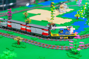 Fototapeta premium Lego train set in a miniature village landscape, featuring a red and white train with gray accents on curving tracks Buildings and greenery strategically placed for - Kyiv, Ukraine - June 7, 2025