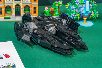 Fototapeta premium Lego spaceship model, dark with blue and grey accents, multiple engines, control panels, vibrant plant backdrop, paper instructions, angled upward perspective, brigh - Kyiv, Ukraine - June 7, 2025