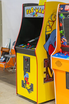 Two classic arcade game machines pac-man, another unidentified game standing side by side in a well-lit room Both have vibrant yellowred, blueorange cabinets wi - Kyiv, Ukraine - June 7, 2025