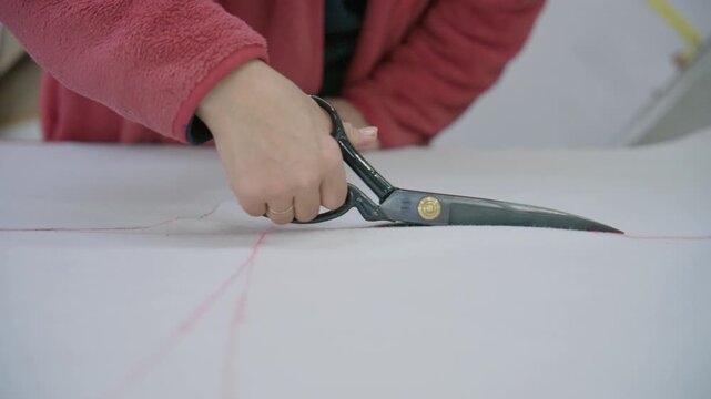 Seamstress hands cutting fabric with scissors