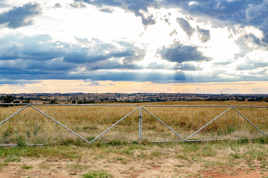 Pair of metal farm gates with countryside in the background and stormy clouds overhead