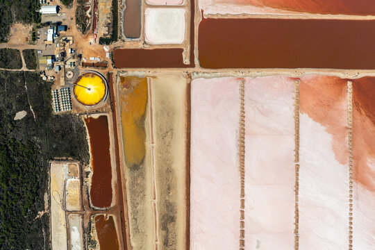 Top-down view of industrial salt pans with pink, orange, and yellow mineral pools.