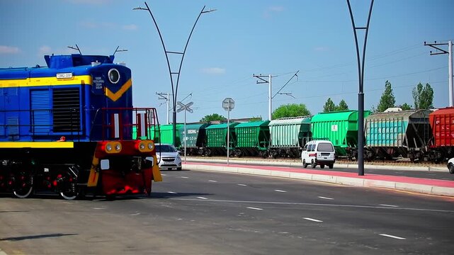 Freight train runs on a sunny day along a highway with cars