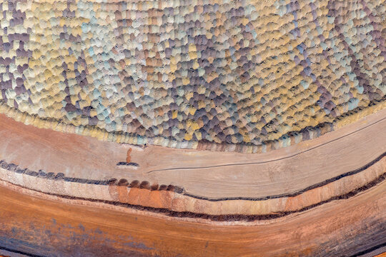 A high-angle abstract view of textured mineral piles and haul roads at an industrial mine site