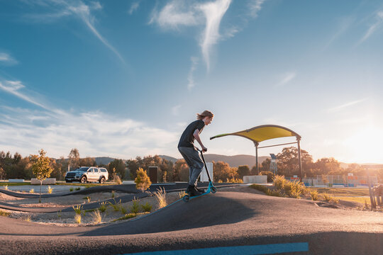 Active teenager riding scooter at pump track