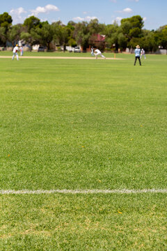 Cricket match in play at a country sports ground; view from the boundary