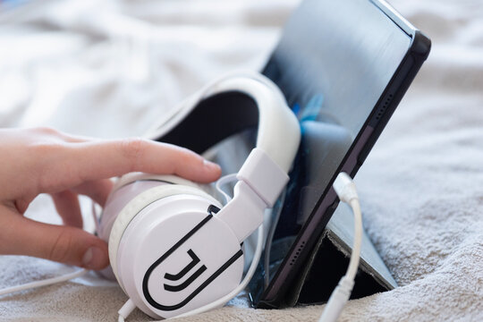 Bratislava, Slovakia, Europe - Mar 07, 2026: close up of juventus football club logo on white headphones near tablet on soft surface, person hand reaching for official Juventus fc branded accessory