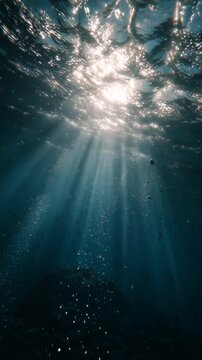 Sunlight rays penetrating through clear underwater ocean water with bubbles.