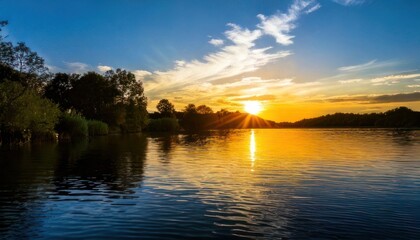 Fototapeta premium Serene sunset over a tranquil lake reflecting golden light.