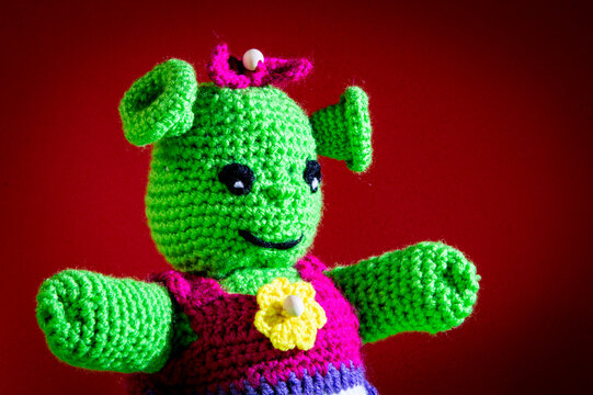 Mu&ntilde;eca verde de ganchillo, ogra simp&aacute;tica con fondo rojo