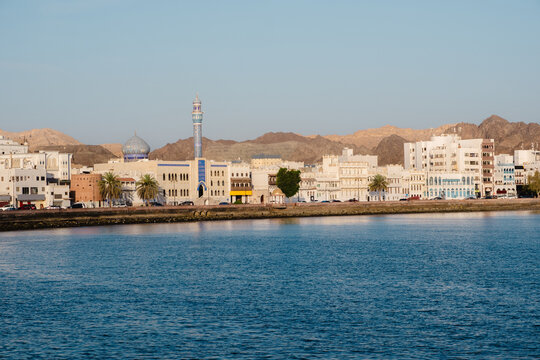 Muscat cityscape from Muttrah Corniche with mosque, Hajar mountains background and coastal architecture
