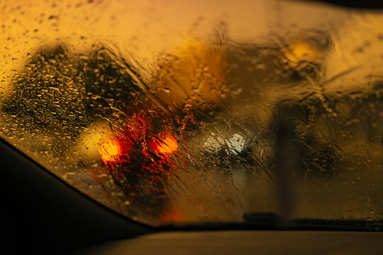 Heavy rain on car windscreen with red lights
