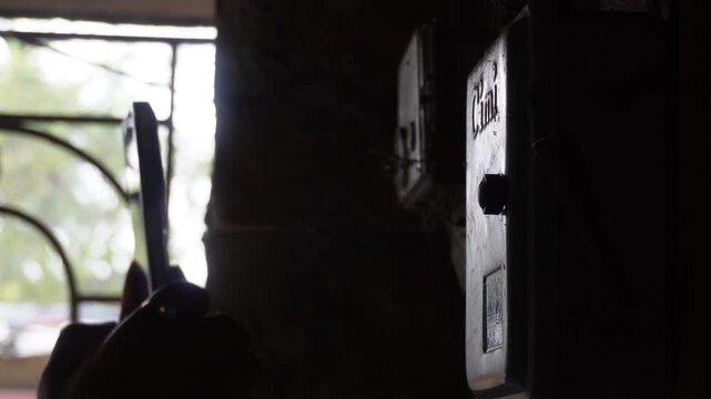 Hand Operating Electrical Meter in Dim Light