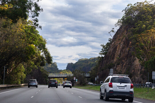 cars travelling on divided highway road with many lanes driving through bushland