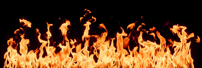 Fototapeta na wymiar Bright orange and yellow flames dance intensely against a dark, black background, creating a dramatic display of heat, power, and energy.