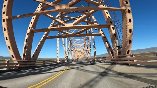 Driving POV crossing The Dalles Bridge over the Columbia River from Oregon toward Washington state, USA. Steel bridge and roadway perspective in scenic Pacific Northwest. 4K transportation b roll