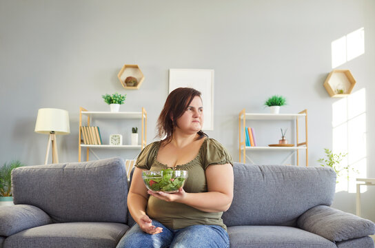 Obese woman sad with healthy salad, unhappy slimming vegetarian diet, eating green vegetables, veggies salad for dinner at home, chubby overweight plus size big fat fit lady no progress in weight loss