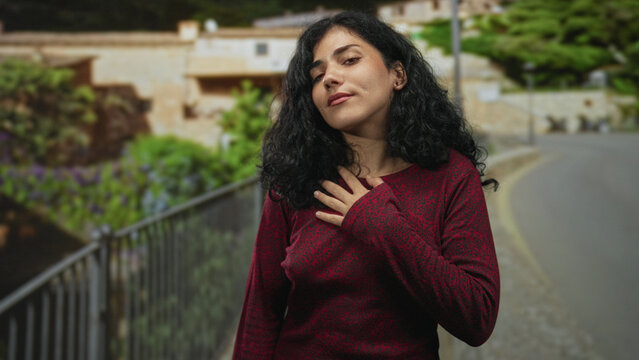 Young woman clutching chest for heartattack on street near railing with closed eyes and cheek piercing; urgent distress breathlessness.