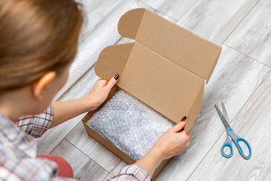 A woman packs goods into a box for shipment by a delivery service. hands packing goods for sale online. A woman at home prepares goods for shipment. startup concept and business ideas. 