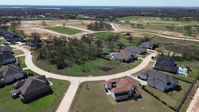 Curved-lot estate homes large mansion houses near Wellington of Flower Mound greenbelt, adjacent undeveloped tracts new construction in residential pocket. Mixed roofing, trimmed lawns, Texas