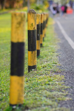 Weathered yellow and black bollards in a grassy area