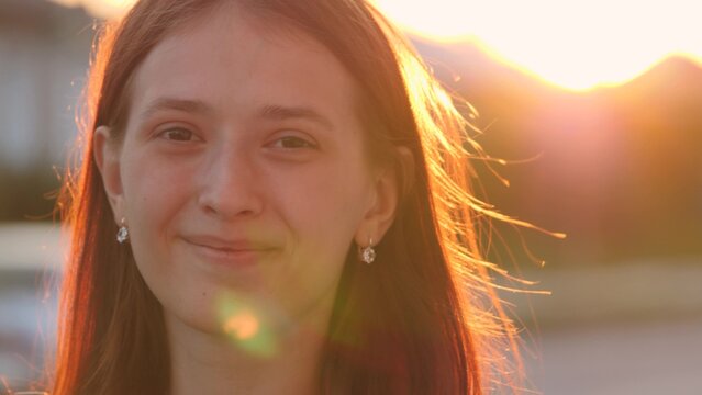 Young happy girl walks down the street smiling at sunset in the city, be satisfied with life, free woman walks in the park, walking, slow motion, student goes to study at dawn at the institute.