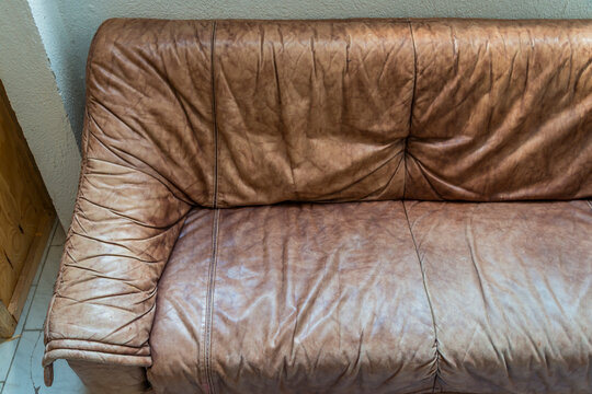Detail eines alten, verratzten Ledersofas aus braunem Leder