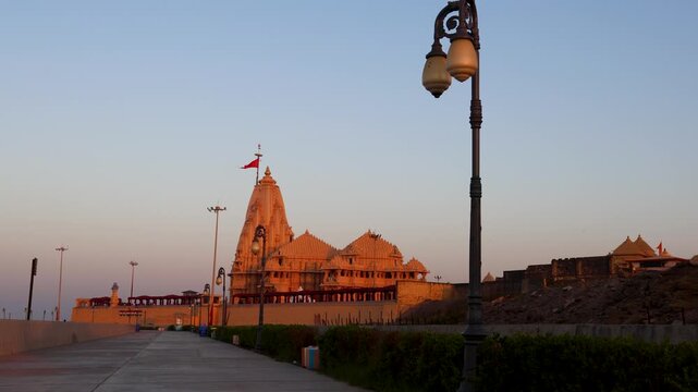 somnath temple illuminated by warm sunset light along coastal walkway in gujarat india