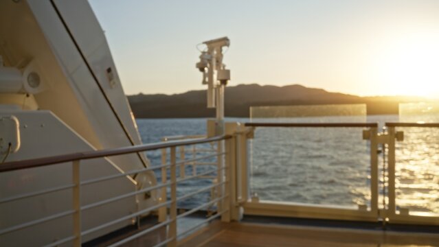 Blurred cruise deck railing and distant shoreline at sunset, soft defocused bokeh outdoor background; background backplate copyspace calm.