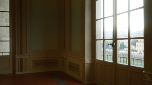 Ornate interior room with defocused bokeh view through tall mullioned windows overlooking a distant city facade, gallery; backdrop copyspace backplate.