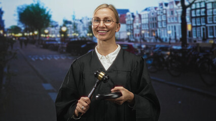 Judge woman holds gavel and block on street by canal buildings, smiling and standing with gavel...