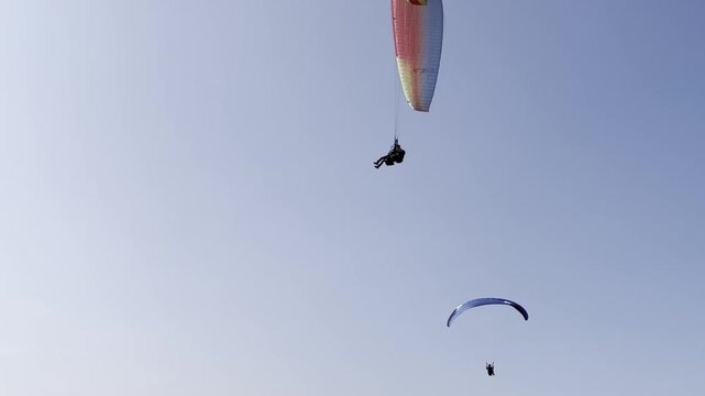 Two paragliders flying in the blue sky on a sunny day