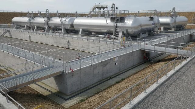 Horizontal storage tanks in a secure tank farm setup surrounded by robust containment dikes and safety walkways highlighting industrial storage safety measures.