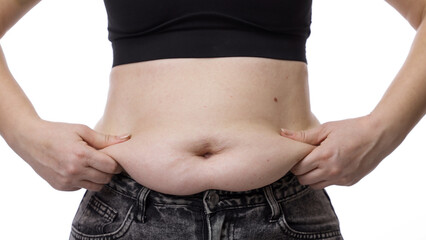 Naklejka premium Unrecognizable overweight woman struggling to put on jeans, showing weight gain challenges. Weight loss concept.