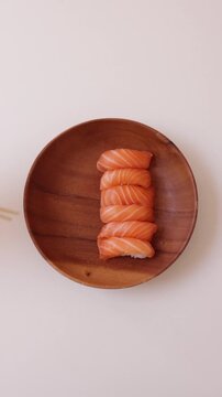 Close up of a person picking up a fresh sushi roll with chopsticks