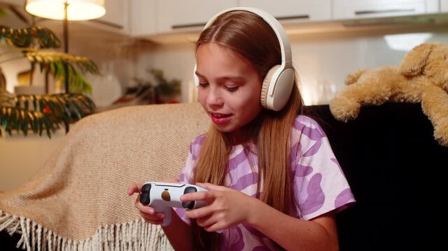 Teenager girl at night home grips game controller plays console title sharp focus tense moment quick. Caucasian child kid on sofa at evening dodges attack scores point breathes deep enjoys free time.