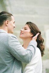 Fototapeta premium Romantic couple close portrait outdoors with man gently touching woman hair, elegant bride and groom sharing intimate moment during wedding day in charming European town