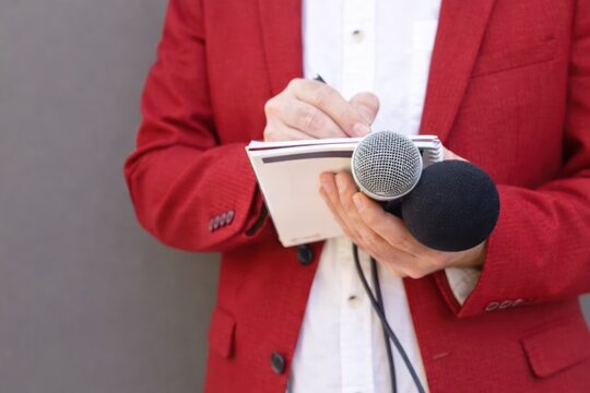 Journalist in Red Jacket Holding Microphones and Notepad taking notes after interview